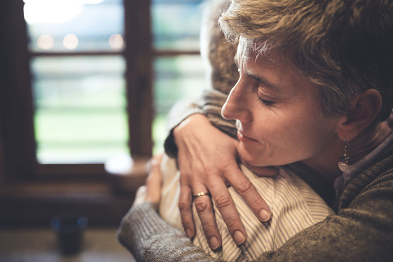 person hugging and comforting senior