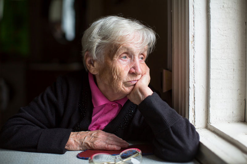 uninterested and sad senior man looking out window